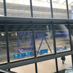 ヒースロー空港内から見える「Trains」案内標識と出発ロビーの風景