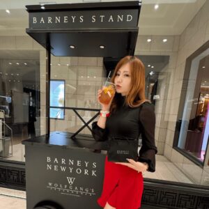 BARNEYS STANDとWolfgang’s Steakhouseのスタンド前でドリンクを持ち微笑む筆者のショット