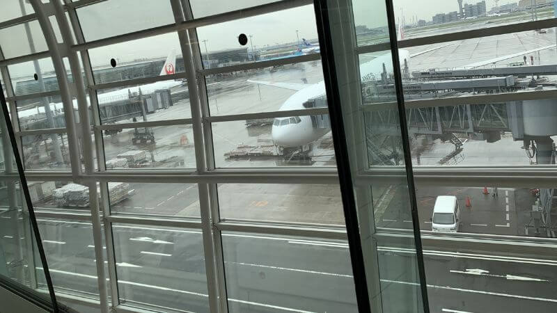 雨の日の羽田空港の滑走路と飛行機の様子