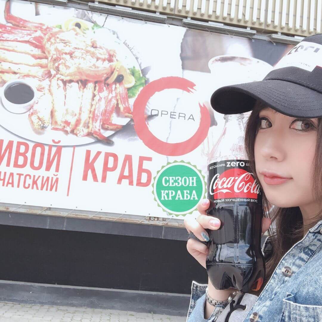ロシアでコーラを持つ筆者とロシア語看板